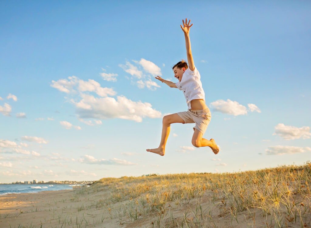 boy jumping off a sand dune into the air
