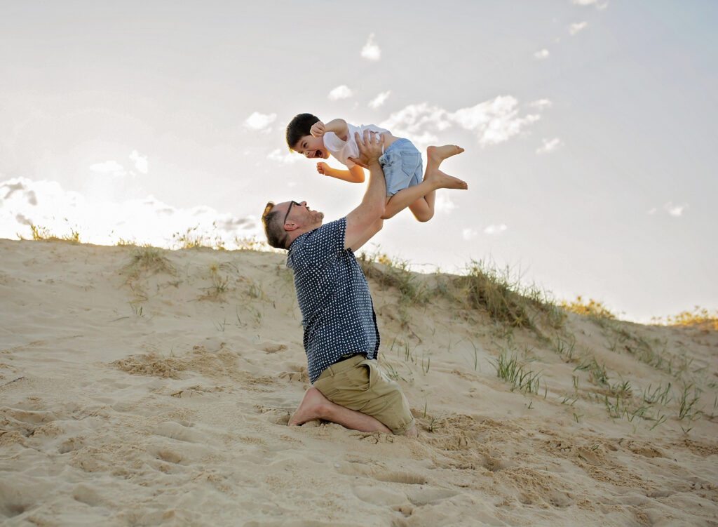 father holding his young son in the air smiling