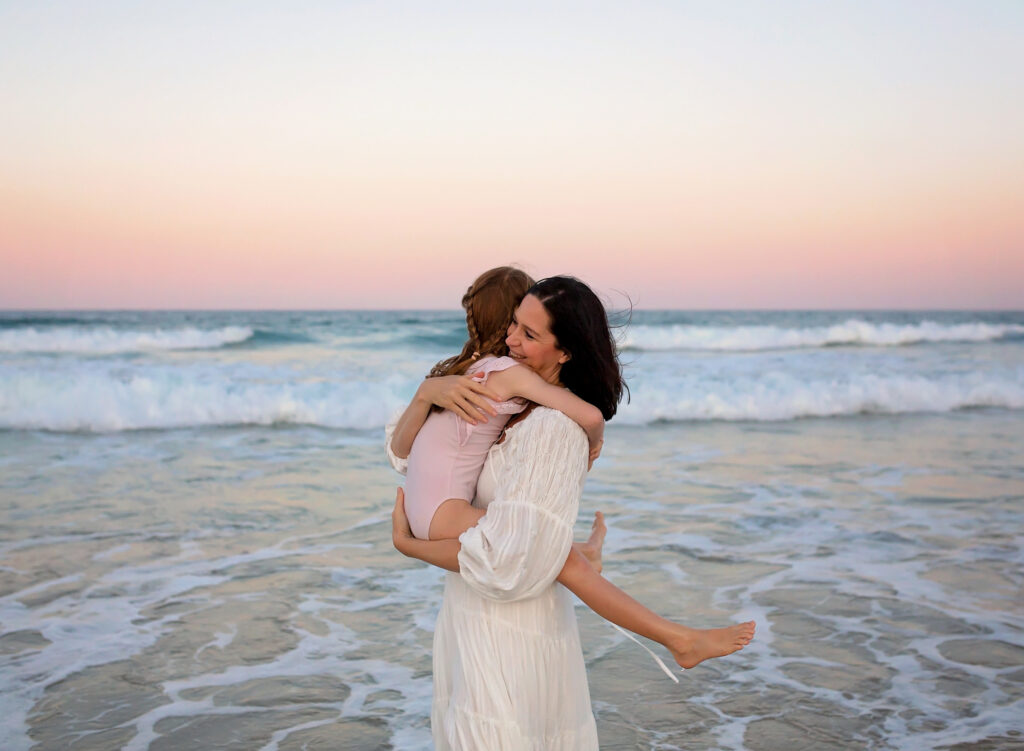 mum hugging her daughter on the beach