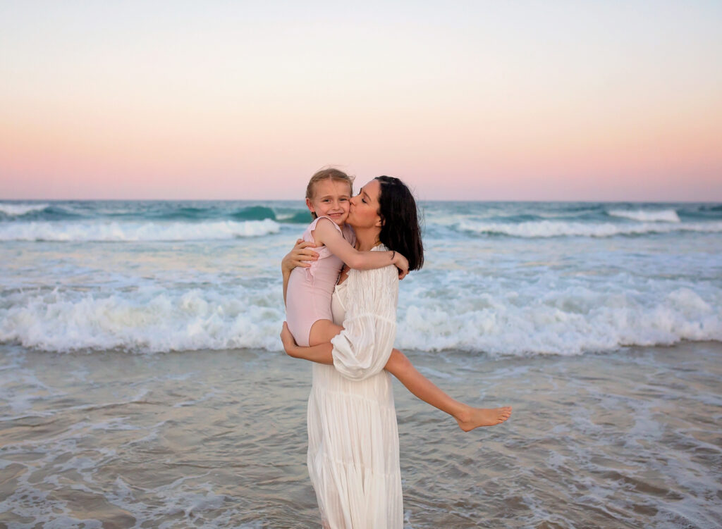 mum hugging her daughter on the beach, mum kissing her daughter on the beach