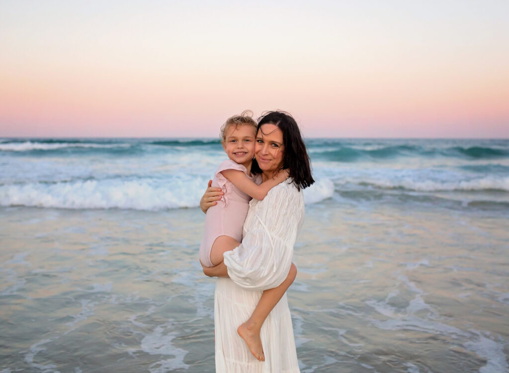 mum hugging her daughter on the beach