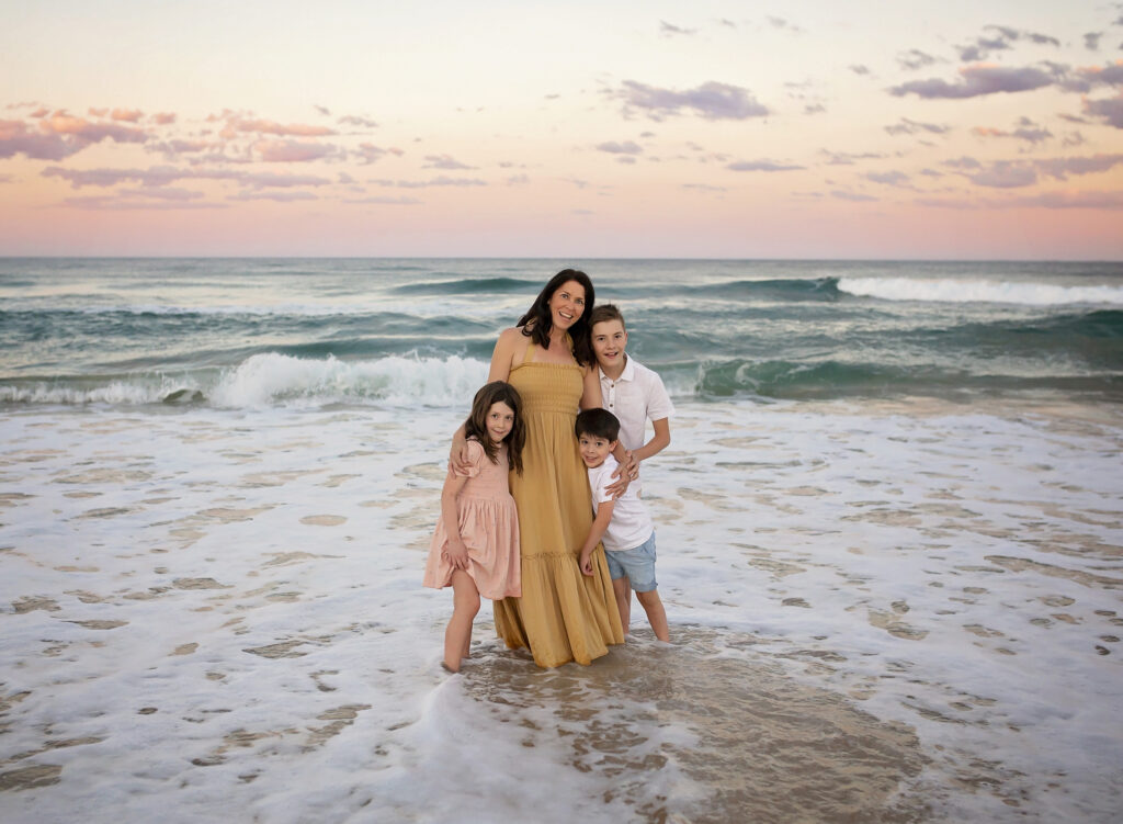 a mother and her 3 children standing in the ocean