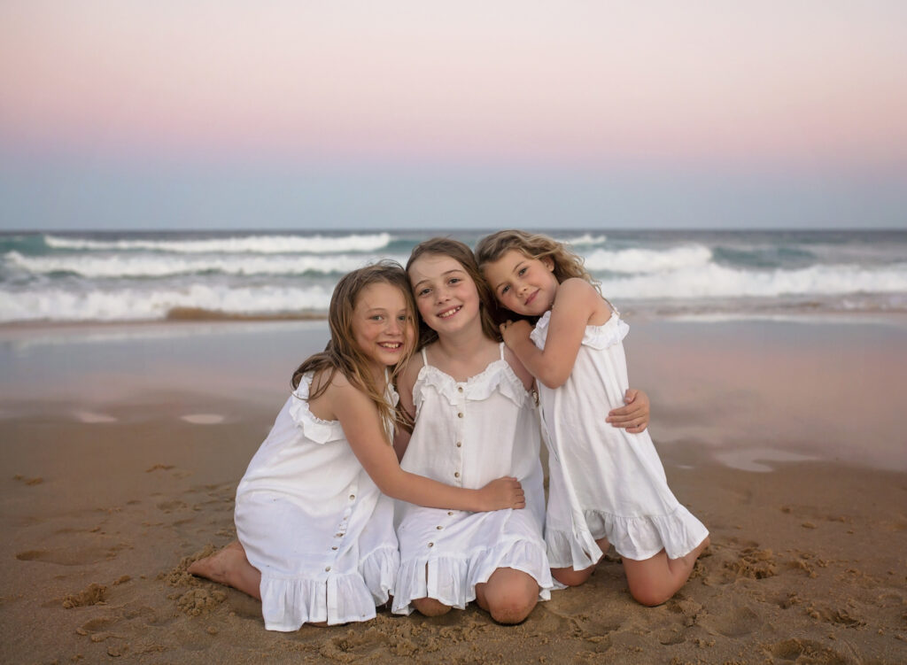 3 sisters hugging on the beach