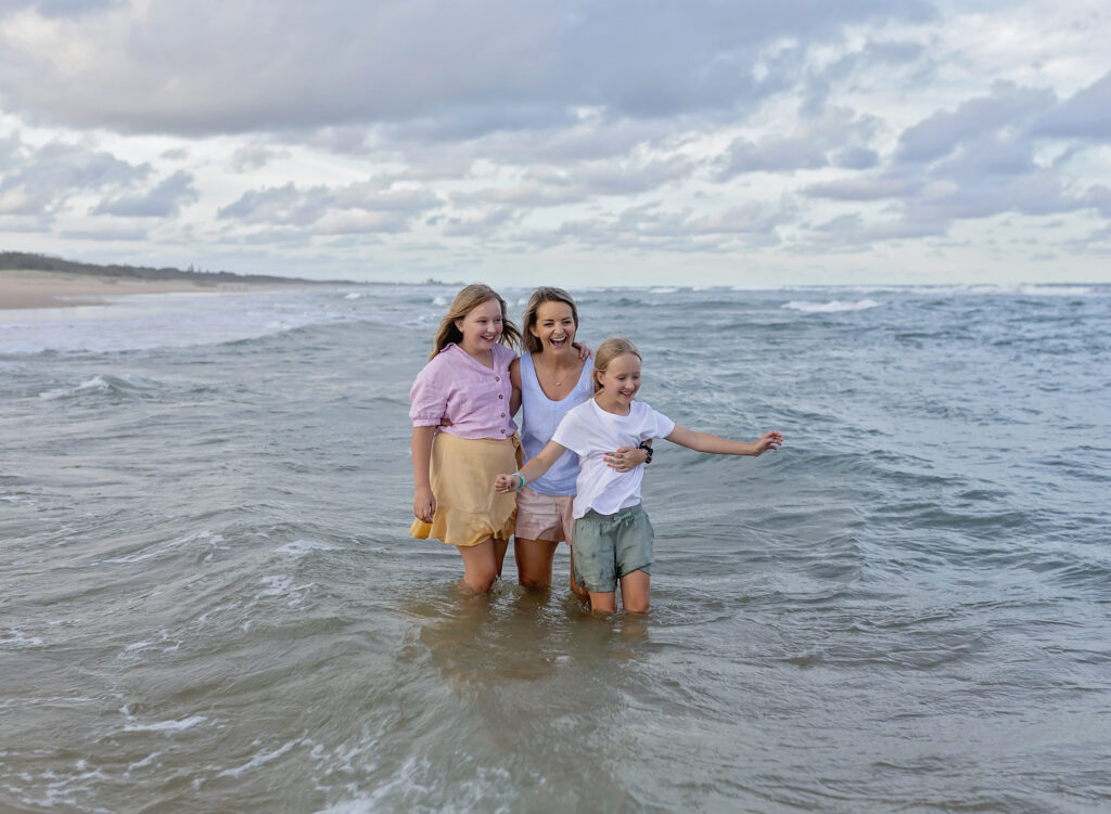 mother and two daughters in the water on the beach