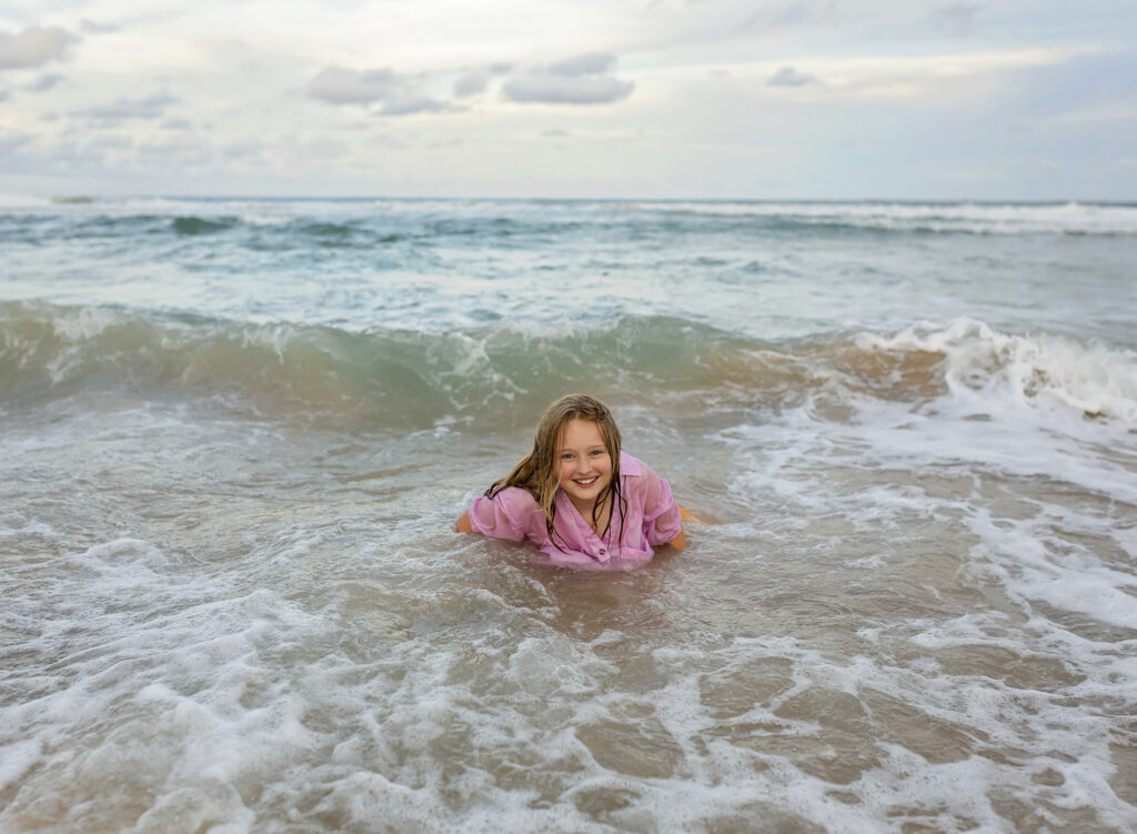 girl in the waves on the beach smiling
