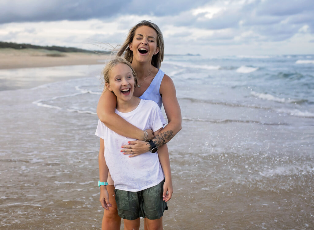 mother and daughter in the water on the beach smiling