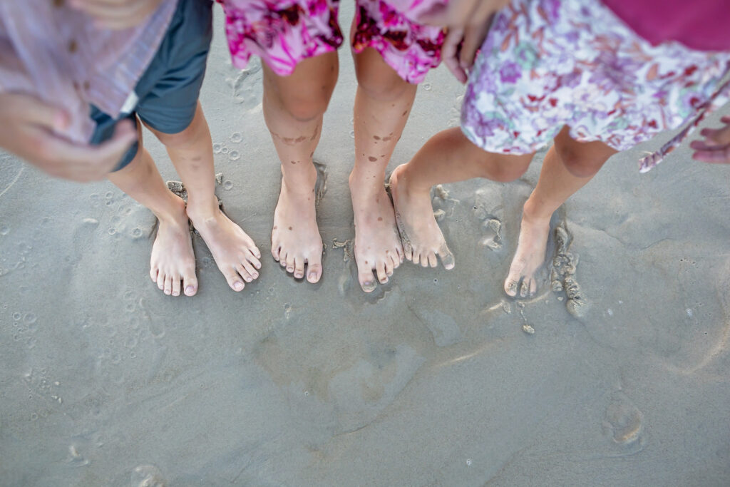 three sets of feet on the sand